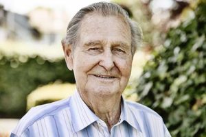 Man smiles outside independent senior living center.