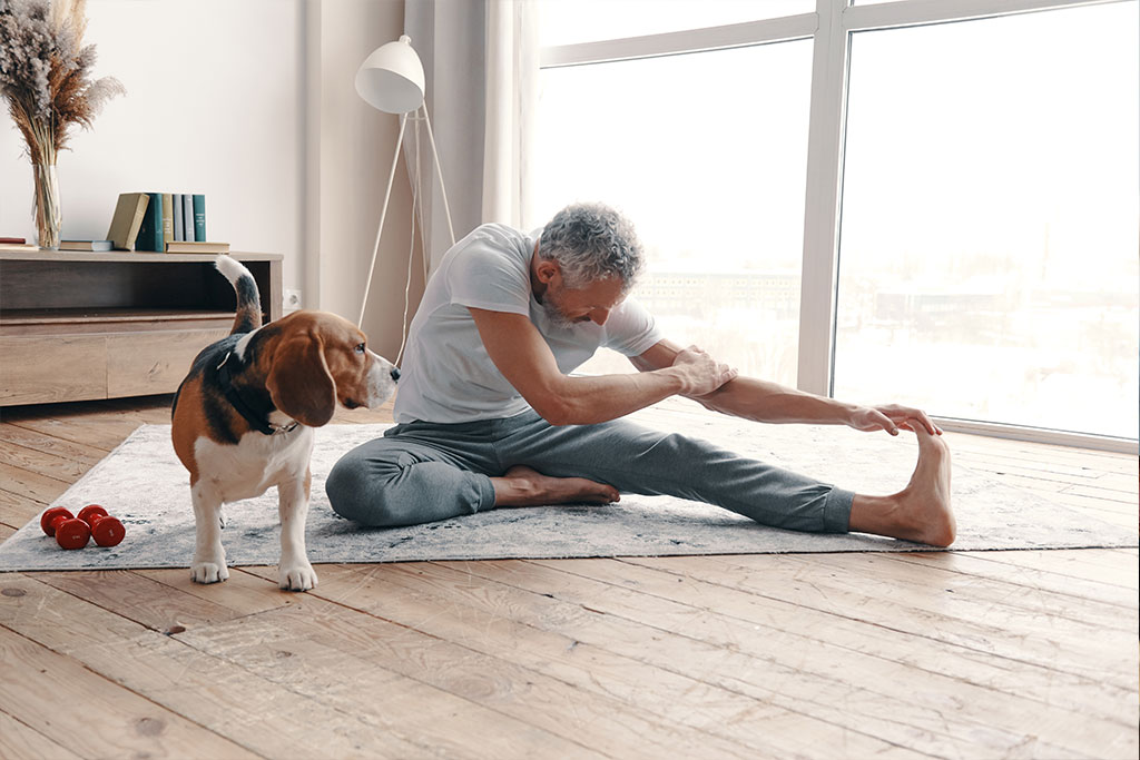 https://www.discoveryvillages.com/wp-content/uploads/2022/04/modern-senior-man-in-sport-clothing-exercising-at-home-near-his-dog.jpg